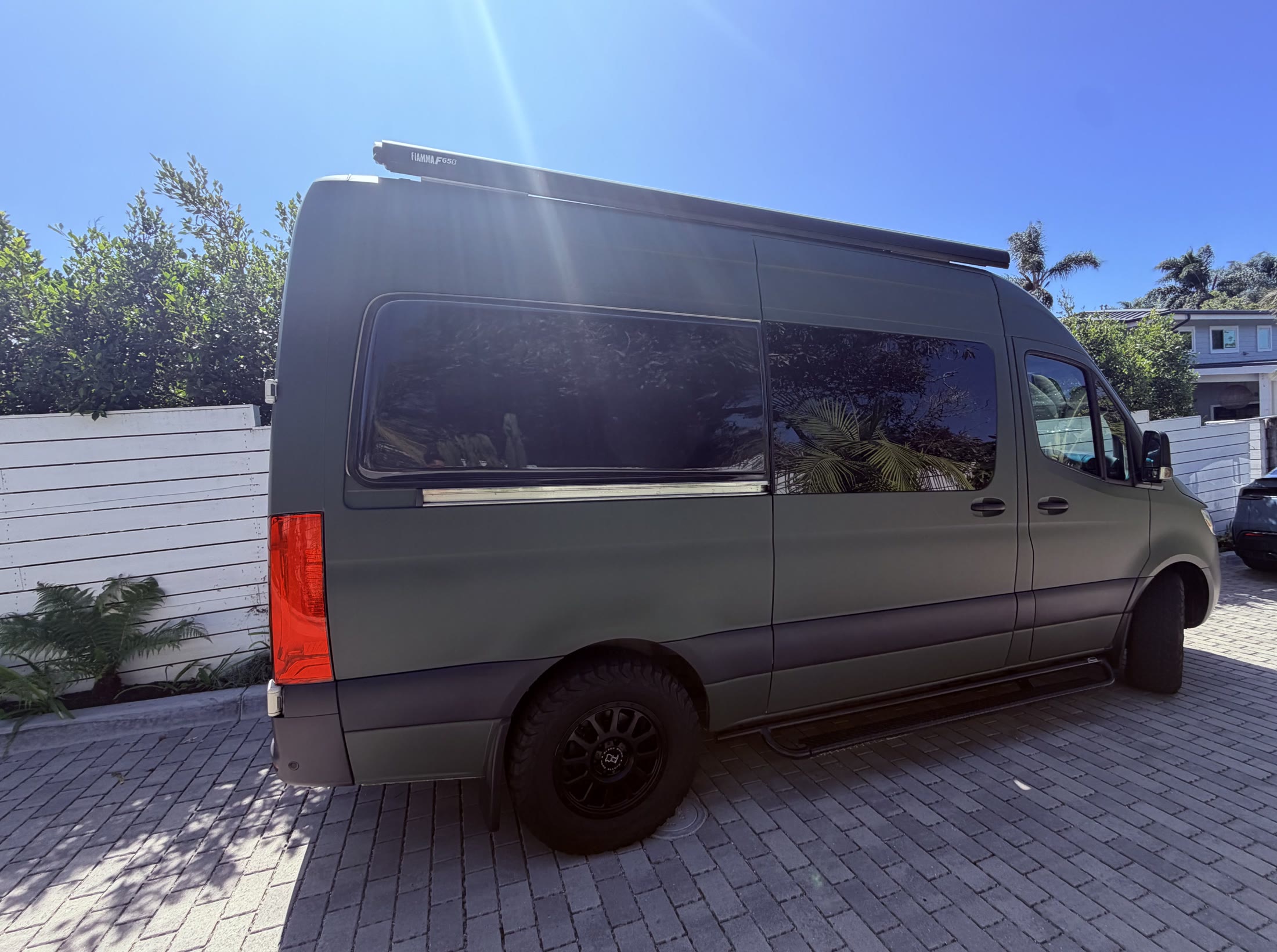 Matte green Mercedes-Benz Sprinter camper viewed from the passenger side