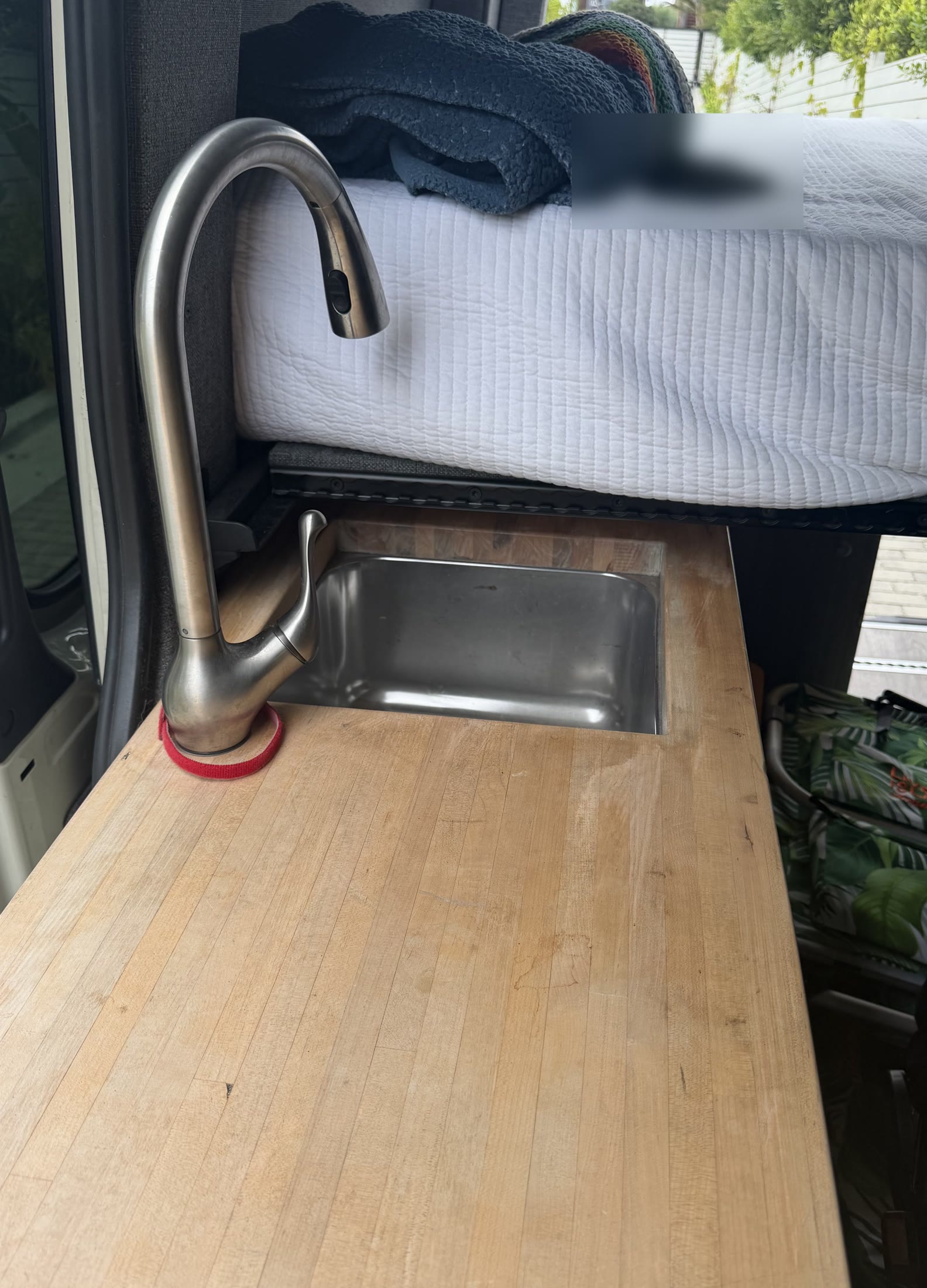Butcher-block counter with stainless sink beside the raised bed